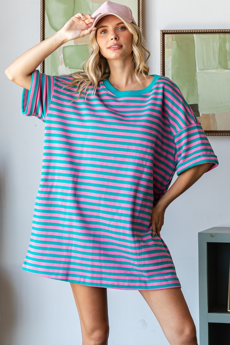 Woman wearing a pink and green striped dress with a cap indoors.