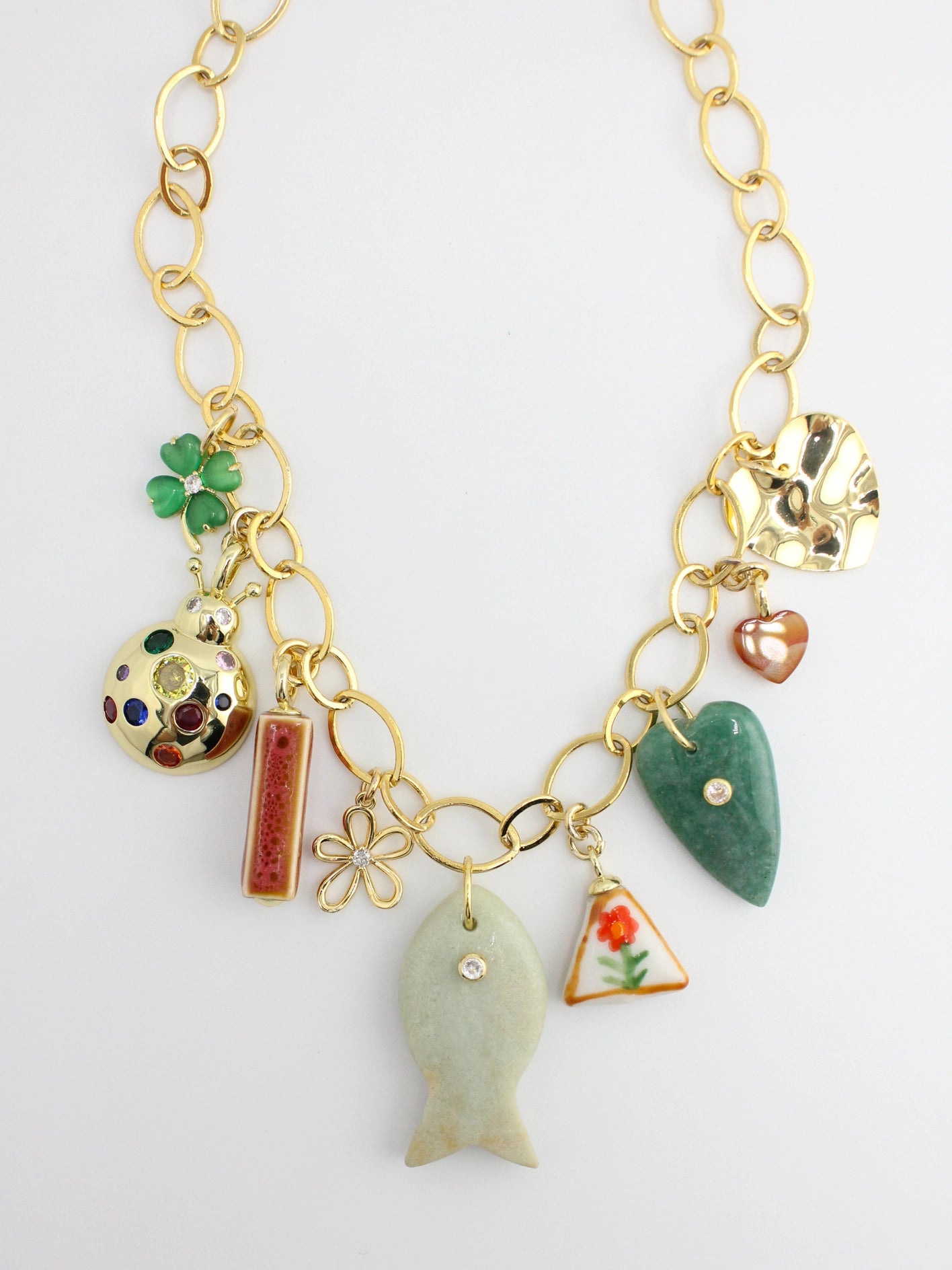Gold necklace with various charms on a white background