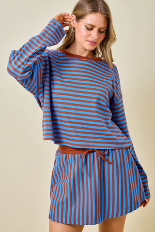 Woman wearing a blue and brown striped outfit on a beige background