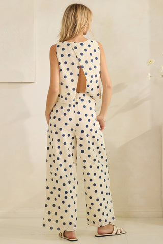 Woman wearing a polka dot jumpsuit with cutout back design.