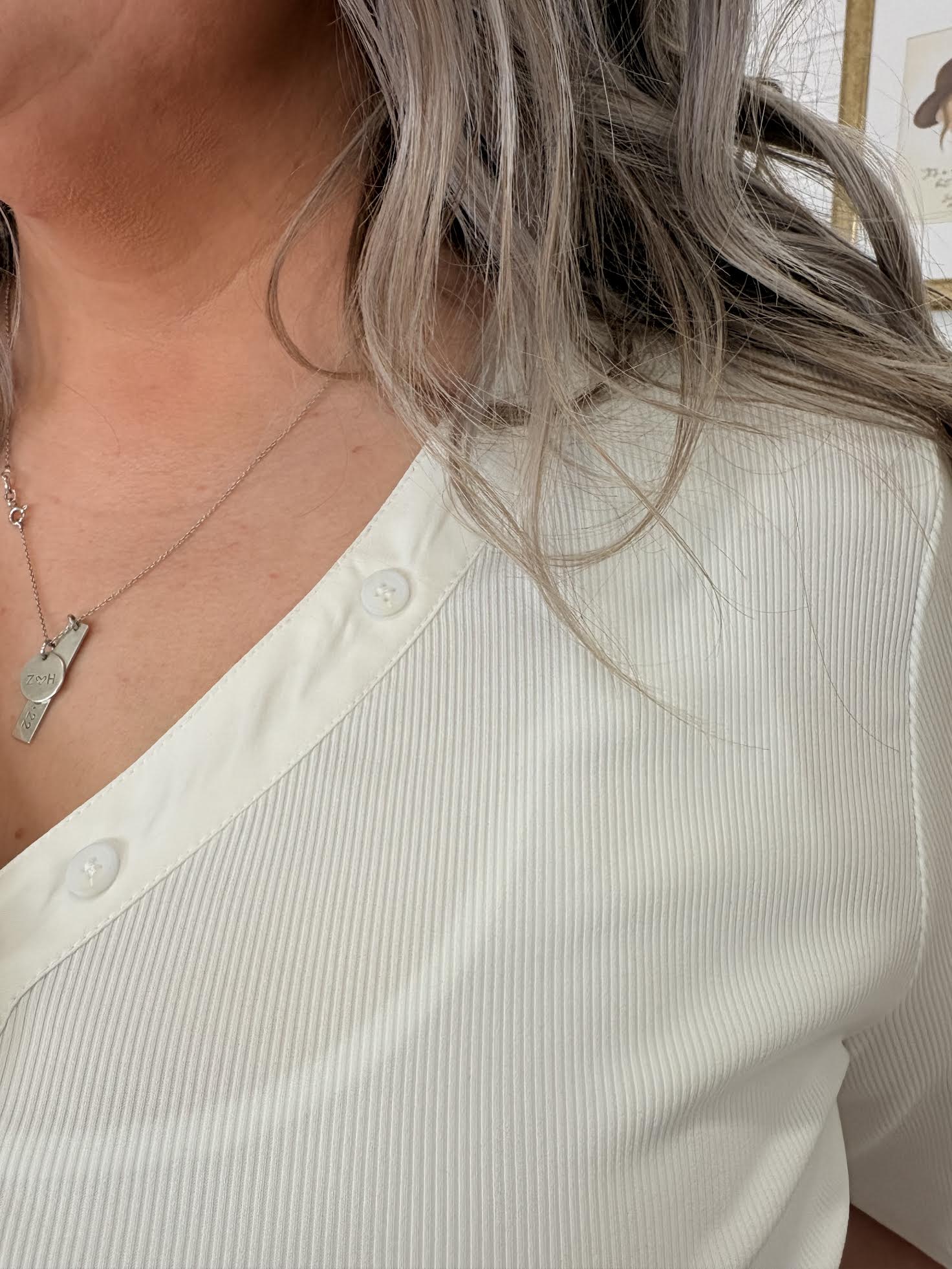Close-up of a person wearing a white shirt and a necklace with a small pendant.