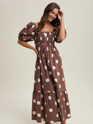 Woman wearing a brown dress with white polka dots on a beige background