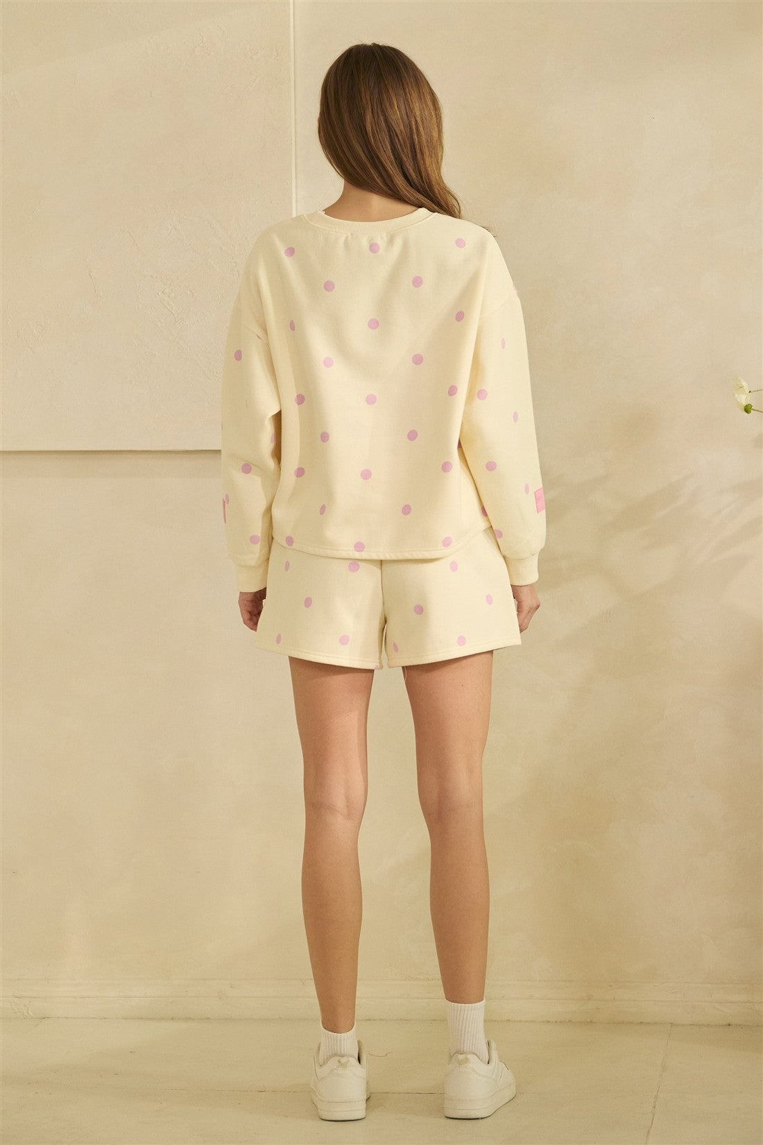 Woman wearing a light yellow pajama set with small patterns against a beige background