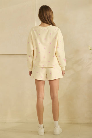 Woman wearing a light yellow pajama set with small patterns against a beige background