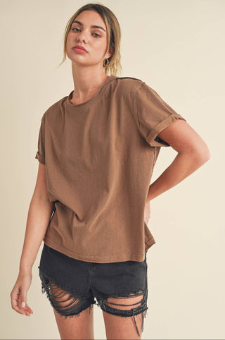 Woman wearing a brown oversized t-shirt and black shorts on a beige background