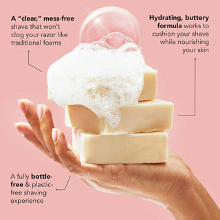 Three bars of soap with a hand holding them, on a pink background with text about the soap's benefits.