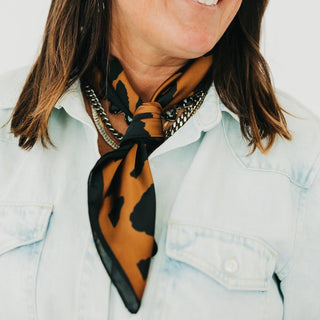 Person wearing a leopard print scarf and light blue denim jacket.