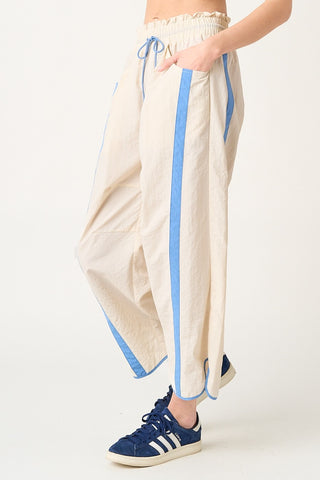 Beige pants with blue stripes worn by a person on a white background