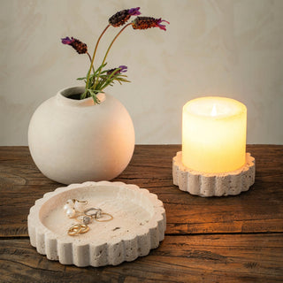 Decorative items including a vase with flowers, a candle in a holder, and a jewelry dish on a wooden surface.