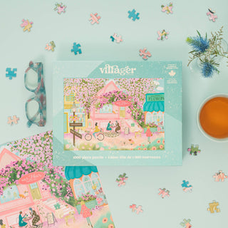 Villager puzzle box with a floral village design on a light blue background with puzzle pieces and a teacup.
