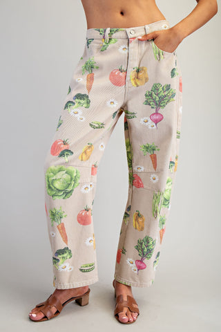 Beige pants with colorful vegetable pattern worn by a person on a gray background