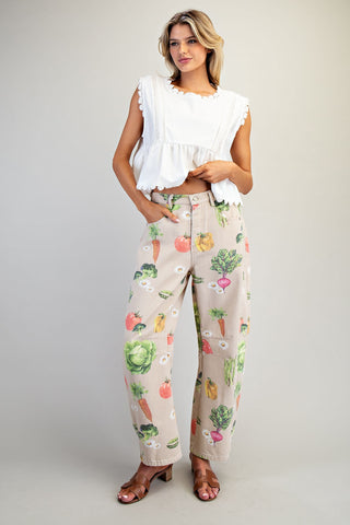 Woman wearing a white blouse and patterned pants with vegetables on a plain background