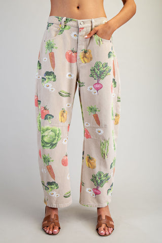 Pants with a colorful vegetable pattern worn by a person on a plain background