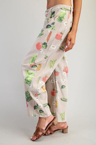 Beige pants with colorful vegetable pattern worn by a person on a plain background