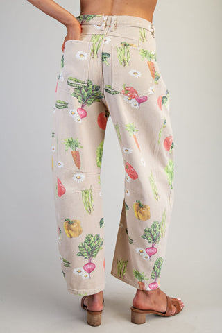 Beige pants with colorful vegetable pattern worn by a person on a plain background