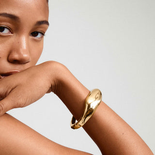 Woman wearing a gold bracelet on a plain background