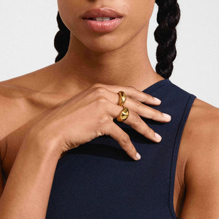 Woman wearing a gold ring on her finger against a neutral background