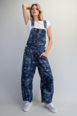 Woman wearing blue floral overalls on a plain background