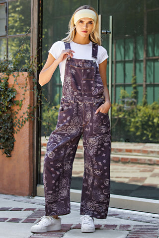 Person wearing a patterned overalls standing outdoors.