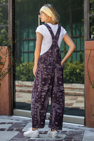 Person wearing a patterned purple jumpsuit standing in front of a building entrance.