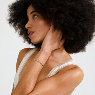 Woman with an afro adjusting her hair against a plain background
