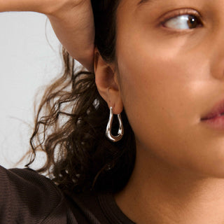 Close-up of a person wearing a silver hoop earring with a blurred background