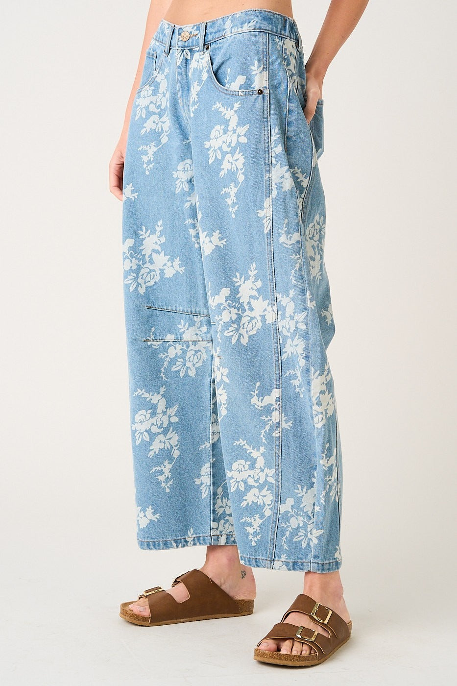 Light blue denim pants with white floral pattern worn by a person on a white background