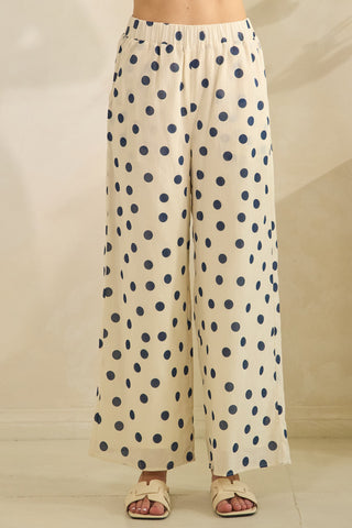 Beige pants with blue polka dots worn by a person on a neutral background