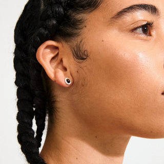 Close-up of a person's ear with a black braided hair style against a white background