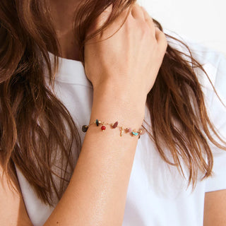 Close-up of a person wearing a bracelet with colorful beads on a plain background