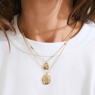 Gold necklaces with pendants on a white shirt
