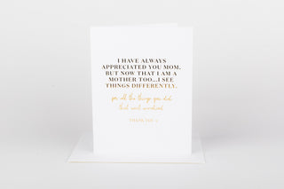 A greeting card with a quote embossed in gold foil on the front, accompanied by a white envelope.