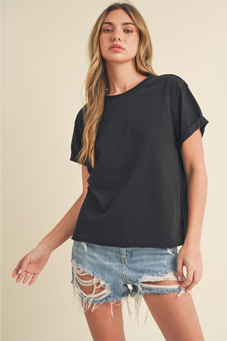 Woman wearing a black oversized t-shirt and denim shorts on a beige background