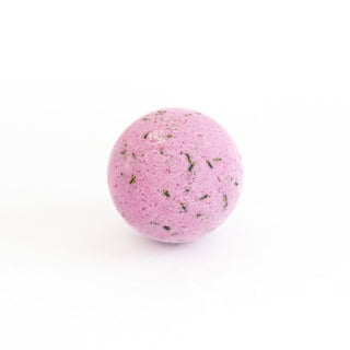 Pink bath bomb with green specks on a white background