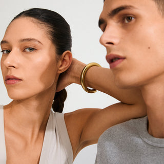 Close-up of a woman wearing a gold earring with a neutral background