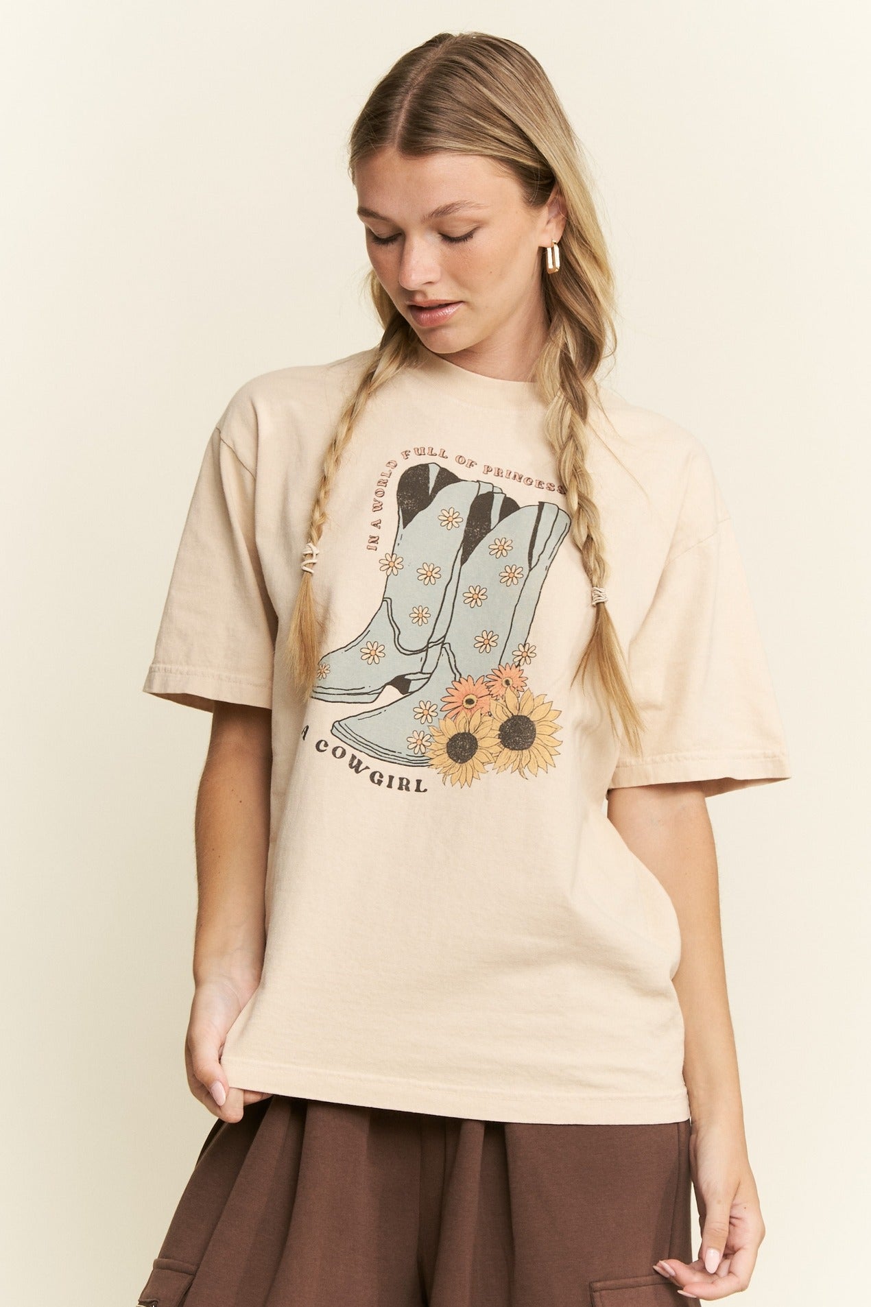 Woman wearing a beige t-shirt with a graphic design on a plain background