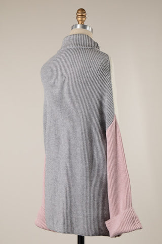 Gray sweater with pink sleeves on a mannequin against a beige background
