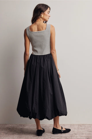 Woman wearing a black dress with a striped top on a plain background