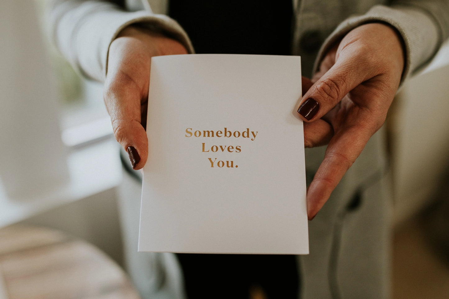 Person holding a card with 'Somebody Loves You' text