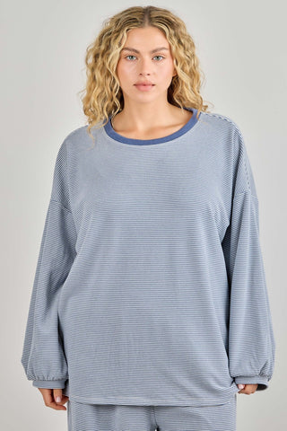 Woman wearing a blue striped long-sleeve top and pants on a gray background