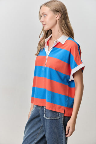 Woman wearing a red and blue striped shirt with a white collar on a plain background