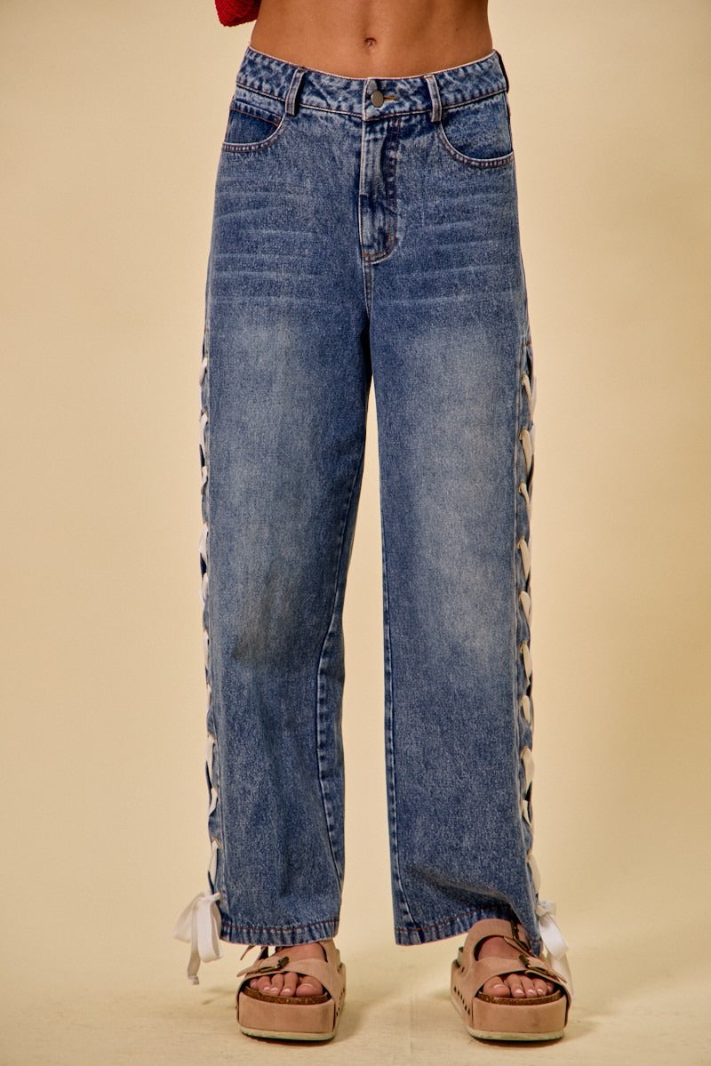 Blue jeans with fringe details on a beige background