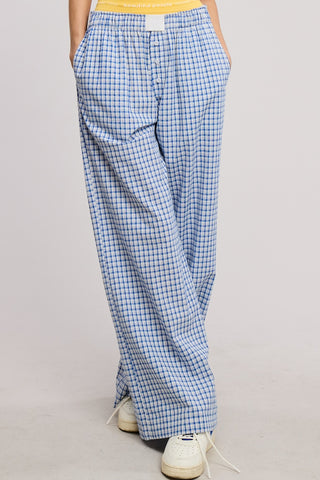Person wearing blue checkered pants on a plain background
