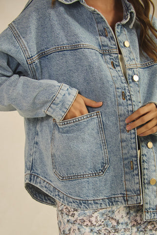Close-up of a person wearing a light blue denim jacket with a neutral background