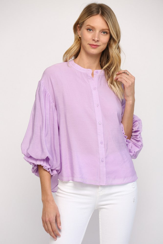 Women wearing a purple blouse with blue jeans on a grey background.