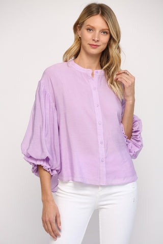Women wearing a purple blouse with blue jeans on a grey background.