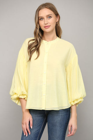 Women wearing a yellow blouse with blue jeans on a grey background.