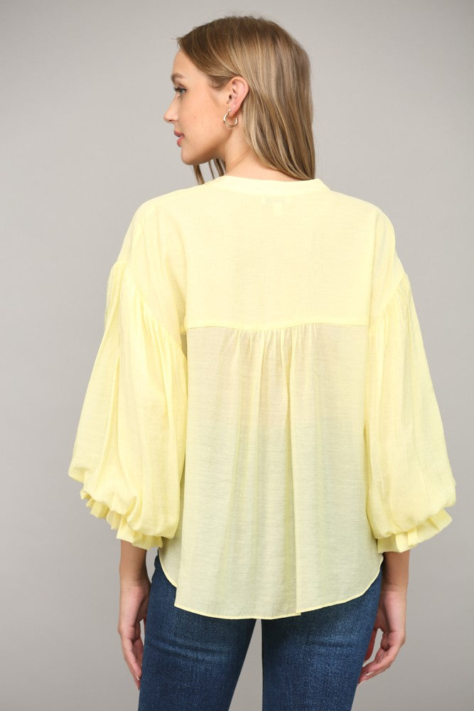 Women wearing a yellow blouse with blue jeans on a grey background.
