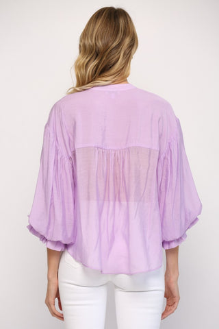 Women wearing a purple blouse with blue jeans on a grey background.