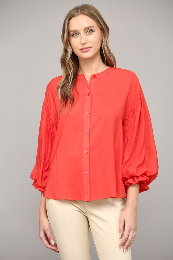 Women wearing a red blouse with blue jeans on a grey background.